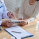 Close-up shot of unrecognizable doctor using digital tablet and discussing records with female patient
